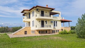 Um edifício residencial com vários andares, varandas, aparelhos de ar condicionado e uma área externa coberta.