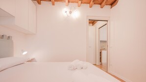 Camera da letto con un letto, una lampada da comodino e asciugamani arrotolati sul letto.