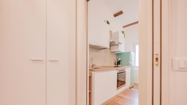 Una cucina moderna con mobili bianchi, una cappa in acciaio inossidabile e un piano di lavoro in legno.
