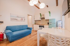 A compact living space with a kitchenette, a dining area, and a sofa. - La Casetta-Stazione Verona Porta Vescovo (Verona)