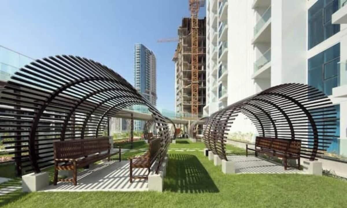 A modern building with a curved architectural design, outdoor seating areas, and a pathway.