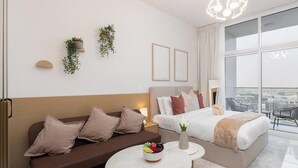 Una habitación de hotel moderna con sofá, cama, una mesa redonda con fruta y vista a la ciudad.