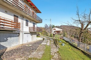A residential building with a stone pathway, a wooden fence, and a clear sky.