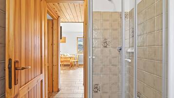 A wooden door leading to a room with a tiled shower wall.