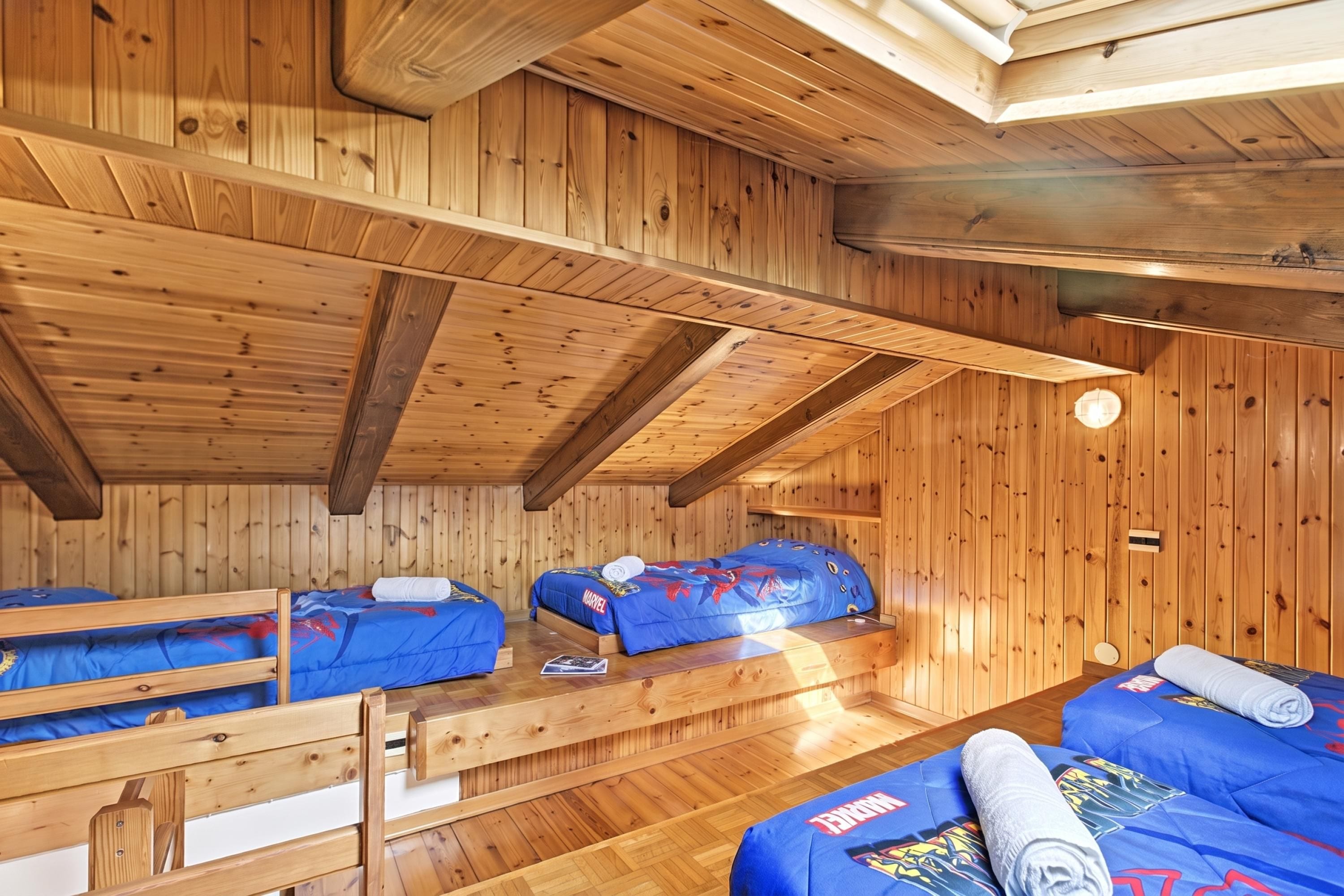 Una cabaña de madera con dos literas, techo de madera y una ventana pequeña.