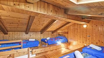 Una cabaña de madera con dos literas, techo de madera y una ventana pequeña.