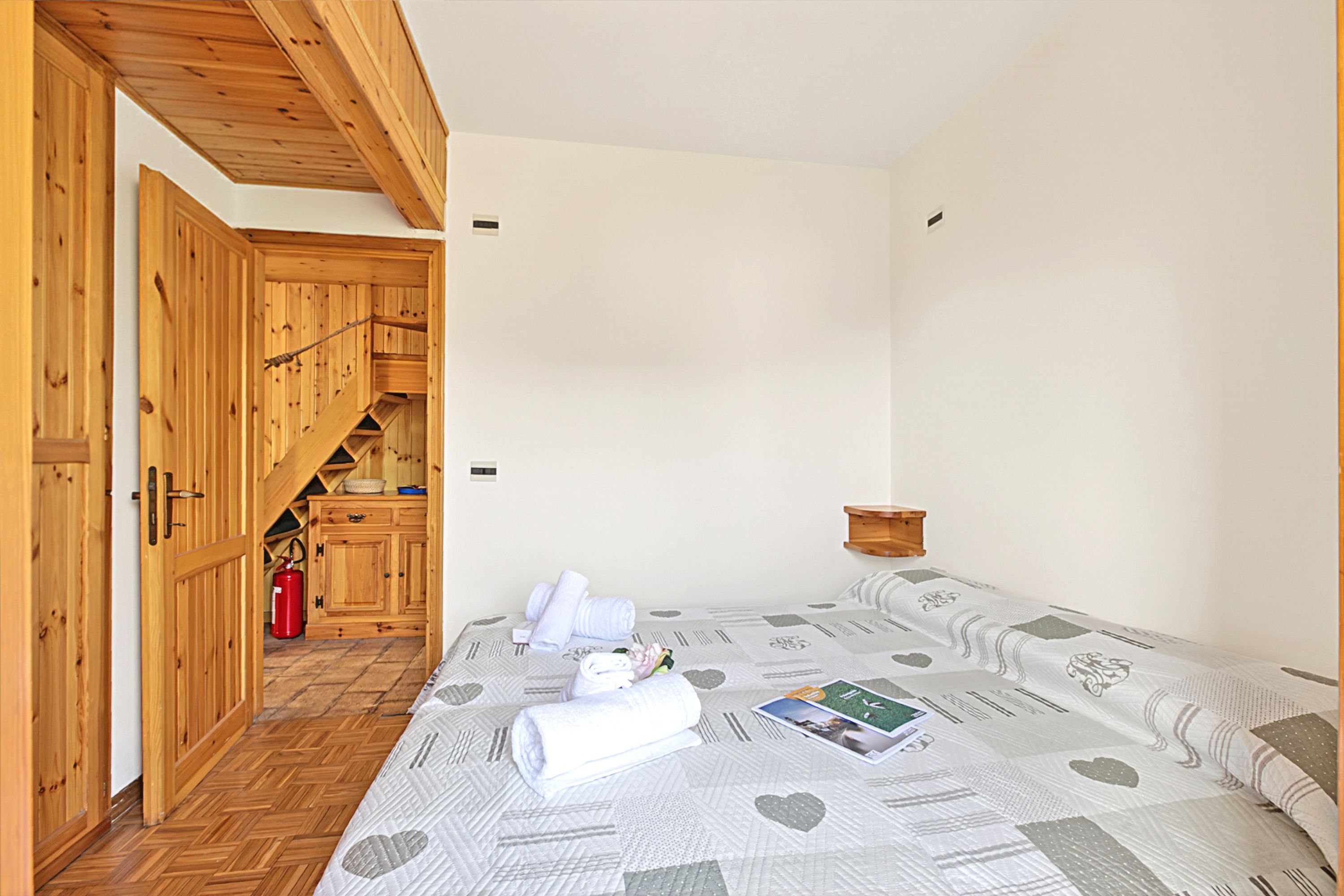 Une chambre avec un lit, une armoire en bois et un petit coin cuisine.