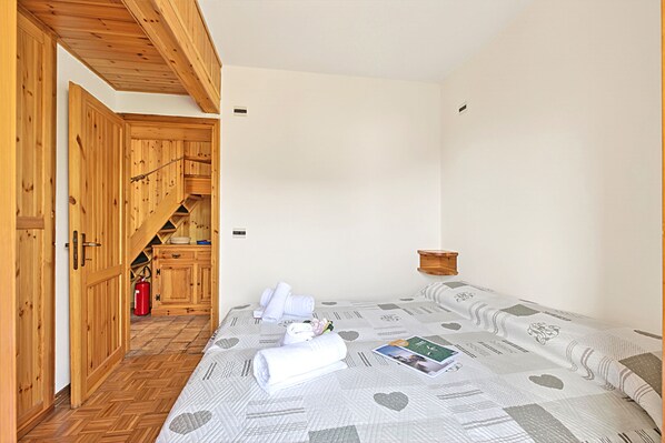 A bedroom with a bed, wooden wardrobe, and a small kitchen area.