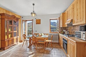 A kitchen with wooden cabinets, a dining table with chairs, a stove, and a microwave.