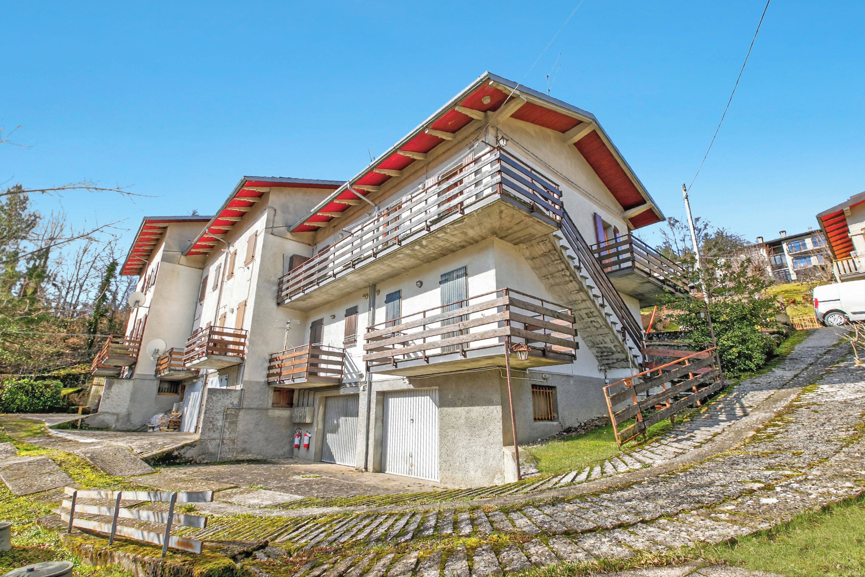 Un edificio de varios pisos con balcones, una escalera y un área pavimentada con escalones que conducen a la entrada.