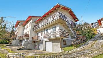 Un edificio de varios pisos con balcones, una escalera y un área pavimentada con escalones que conducen a la entrada.