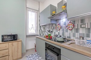 Cocina compacta con microondas, fregadero, estufa y armario de madera.
