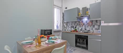 A modern kitchen with grey cabinets, a wooden dining table, and a microwave.
