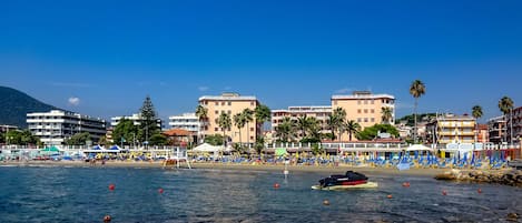 Zona costera con playa, edificios y un bote.