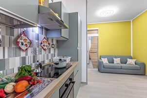 Una cocina moderna con estufa integrada, cafetera y una variedad de verduras frescas sobre la encimera.