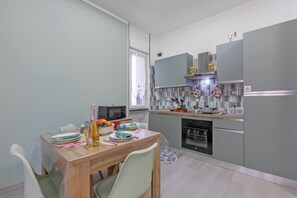 A modern kitchen with grey cabinets, a wooden dining table, and a microwave. - La Genzianella - Studio for 4 With Balcony & AC (Andora)