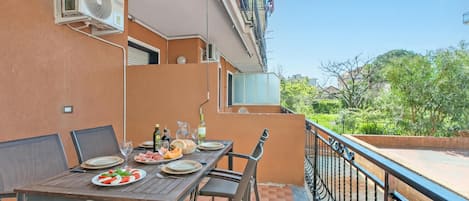 Un área de comedor al aire libre con una mesa lista para dos personas, sillas y vistas a la vegetación.