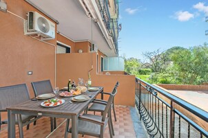 Un área de comedor al aire libre con una mesa lista para dos personas, sillas y vistas a la vegetación.