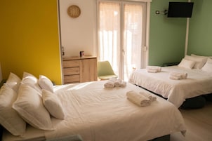 Habitación de hotel con dos camas, un escritorio, una silla, un televisor y un reloj en la pared.