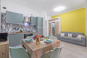 A modern kitchen with grey cabinets, a dining table set with plates, glasses, and a bottle. - La Genzianella - Studio for 4 With Balcony & AC (Andora)