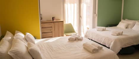 A hotel room with two beds, a desk, a chair, a TV, and a clock on the wall.