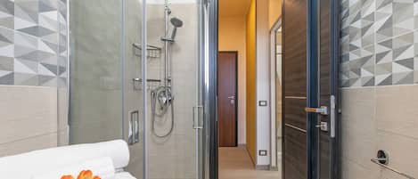 Un baño moderno con cabina de ducha de vidrio, una toalla y una puerta que da a un pasillo.
