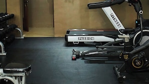 A gym with a stationary bike, dumbbells, and a treadmill.