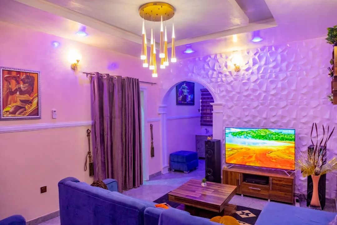 A living room with a sofa, a coffee table, a TV, and a decorative wall.