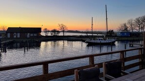 Een uitzicht op het water met een steiger, een boot en gebouwen op de achtergrond.