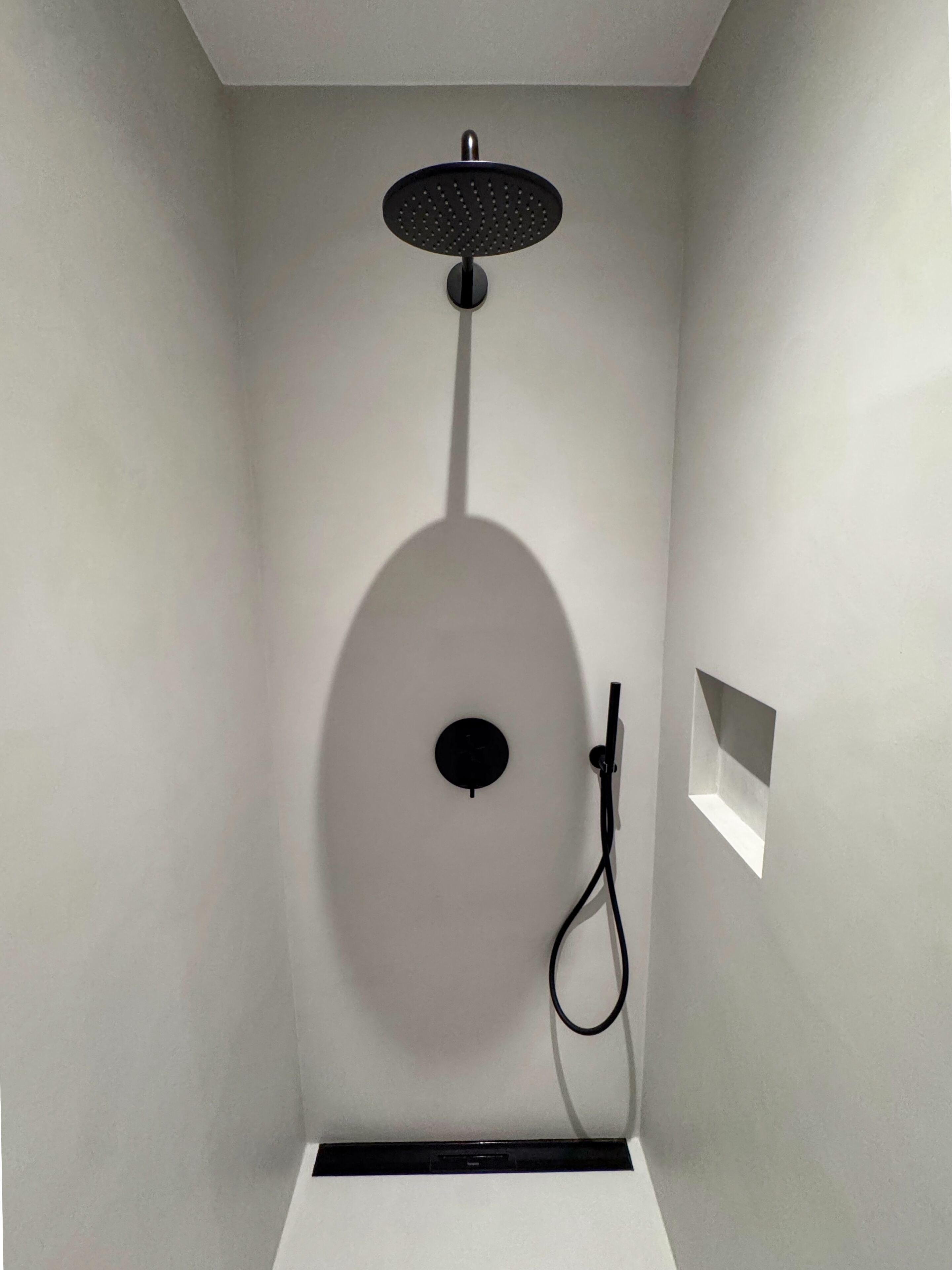 Eine moderne Dusche mit Runddusche, Drehregler und Handbrause.