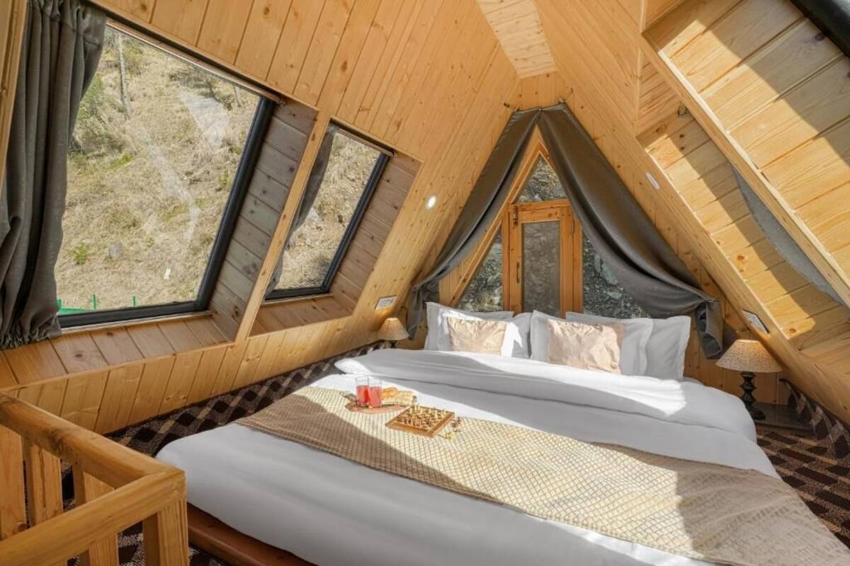 A cozy bedroom with a bed, pillows, a nightstand, and a window.