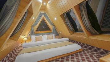 Een zolderkamer met een driehoekige vorm, een bed, een raam en een lamp.