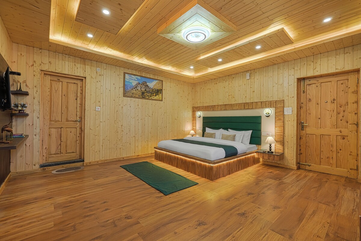 A wooden-paneled bedroom with a bed, nightstands, and a green rug.