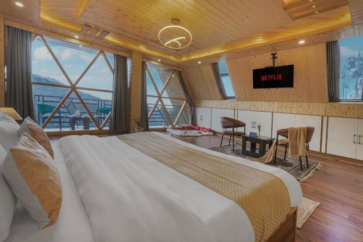 A bedroom with a large bed, a TV, and a view of the outdoors.