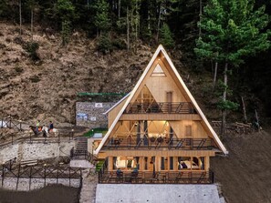 A wooden cabin with a triangular roof, a balcony, and a staircase leading to the upper level. - The Bagh Kufri (Theog)