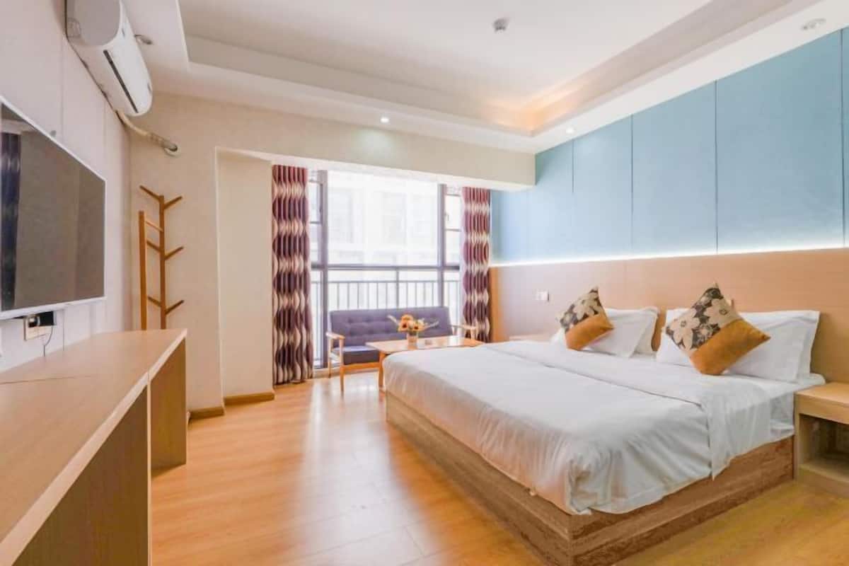 Una habitación de hotel moderna con una cama grande, televisión, escritorio y vistas al exterior.