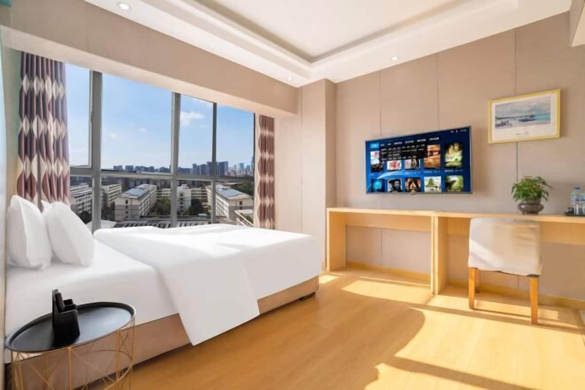 Una habitación de hotel moderna con una cama grande, un escritorio y vistas a la ciudad.