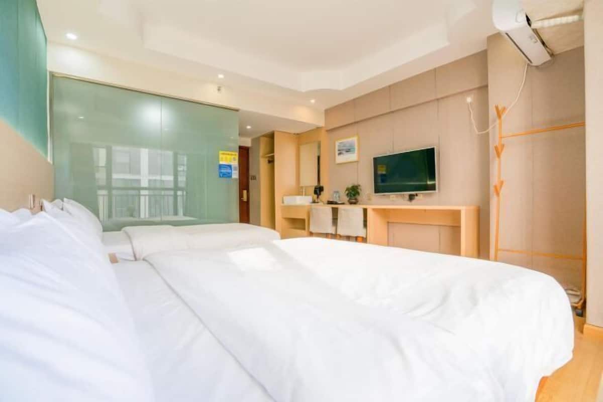 Habitación de hotel con una cama grande, un escritorio, televisión y vistas al exterior.
