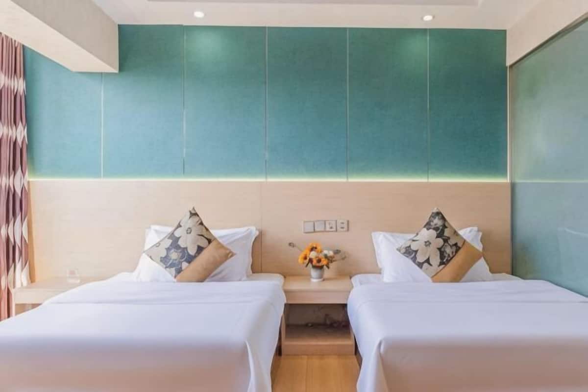Una habitación de hotel con dos camas, una mesita de noche y un florero con flores.