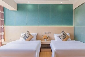 Ein Hotelzimmer mit zwei Betten, einem Nachttisch und einer Blumenvase.
