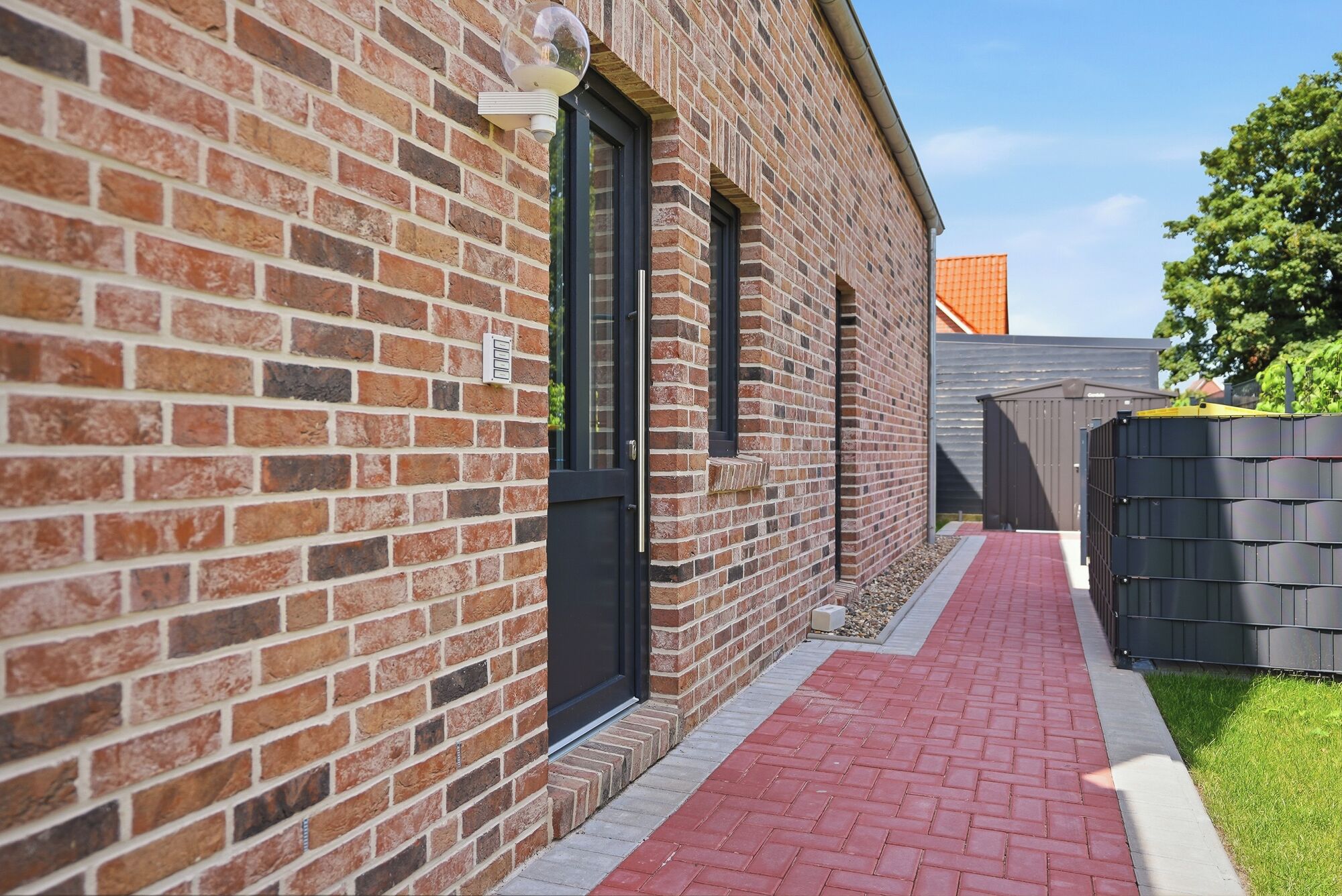 A brick building with a red brick pathway leading to a black door.