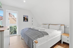 Une chambre à coucher avec un lit, une table de chevet et une vue sur un immeuble par la fenêtre.
