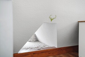 A corner of a room with a wooden floor, a white textured wall, and a small green plant on the wall. - New Platzhirsch vacation apartment in Greetsiel for a relaxing vacation (Greetsiel)