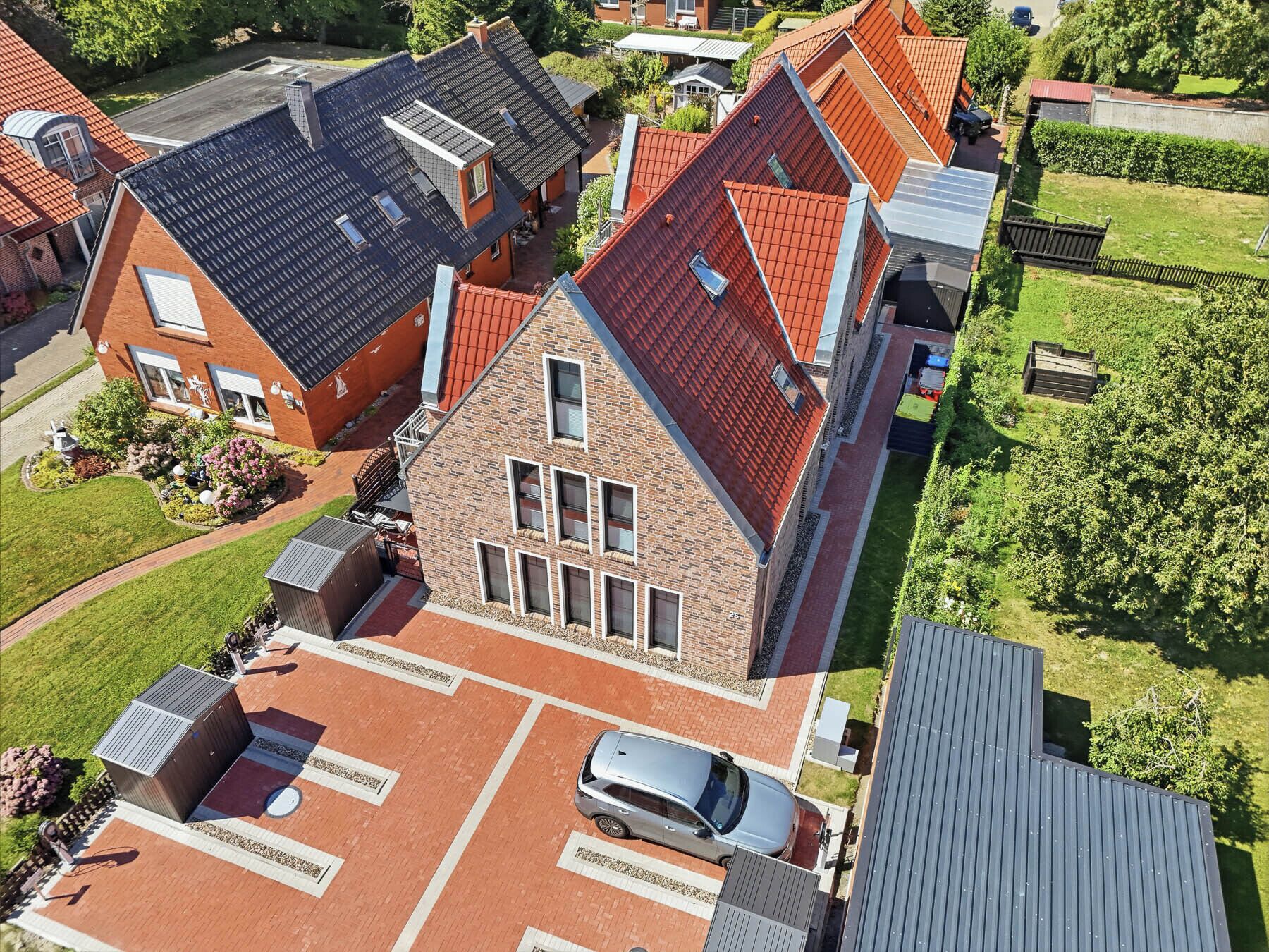 A residential building with a red-tiled roof, a garage, and a paved driveway.