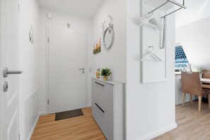 Un pasillo moderno y minimalista con una puerta, un archivador pequeño y un espejo en la pared.