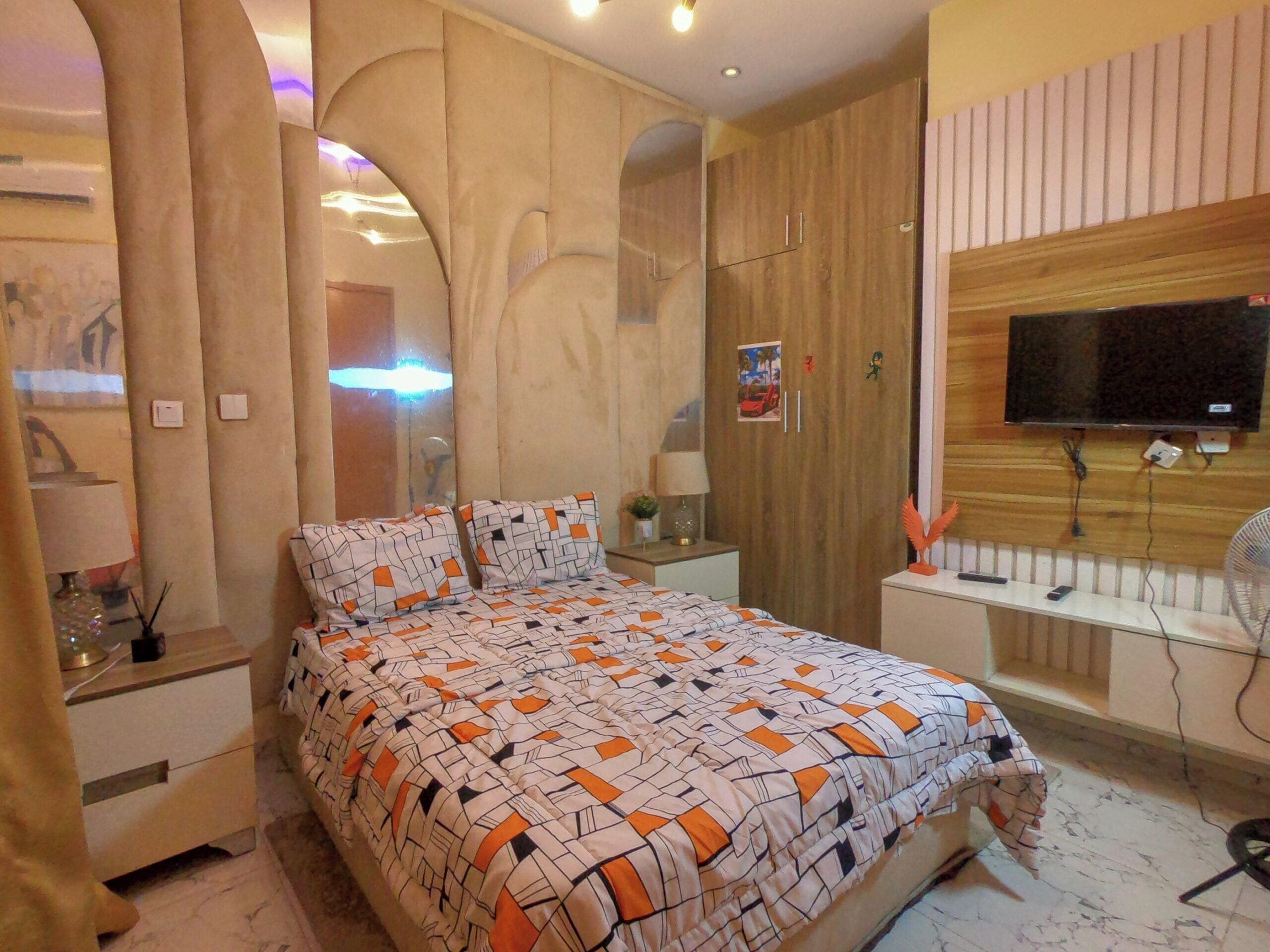A bedroom with a bed, nightstands, a TV, and a mirror.