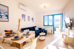 Ein modernes Wohnzimmer mit Essbereich, einem blauen Sofa und einem großen Fenster.