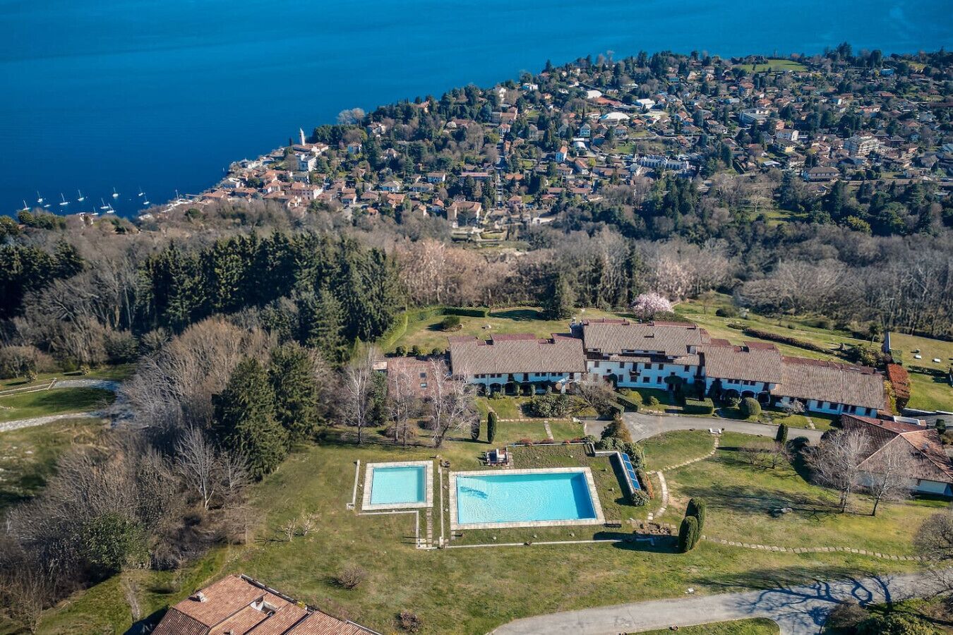 Vue aérienne d’une propriété située sur la côte, avec un grand bâtiment, deux piscines et un paysage environnant.