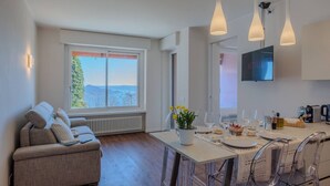 A modern kitchen with a dining area, a sofa, and a TV. - A Ca` di Chiara e Fabio - Panoramica Lago Maggiore (Lesa)