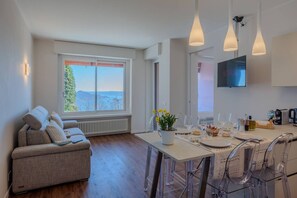 A modern kitchen with a dining area, a sofa, and a TV. - A Ca` di Chiara e Fabio - Panoramica Lago Maggiore (Lesa)